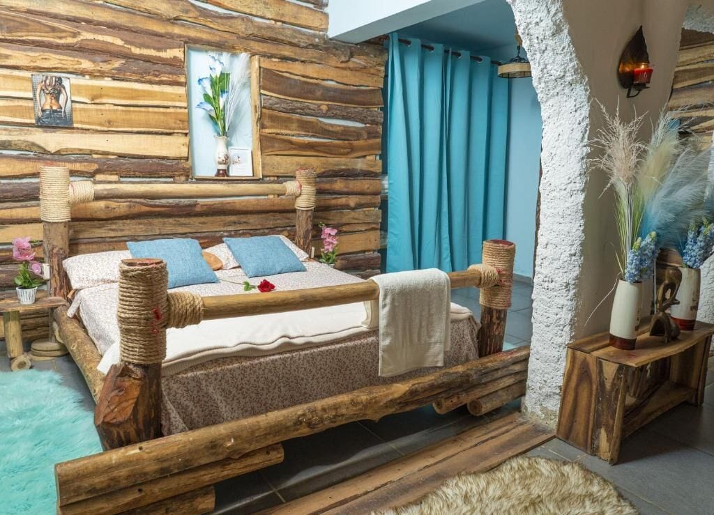 A rustic wooden bed with a white bedspread, blue pillows, and a decorative rose.