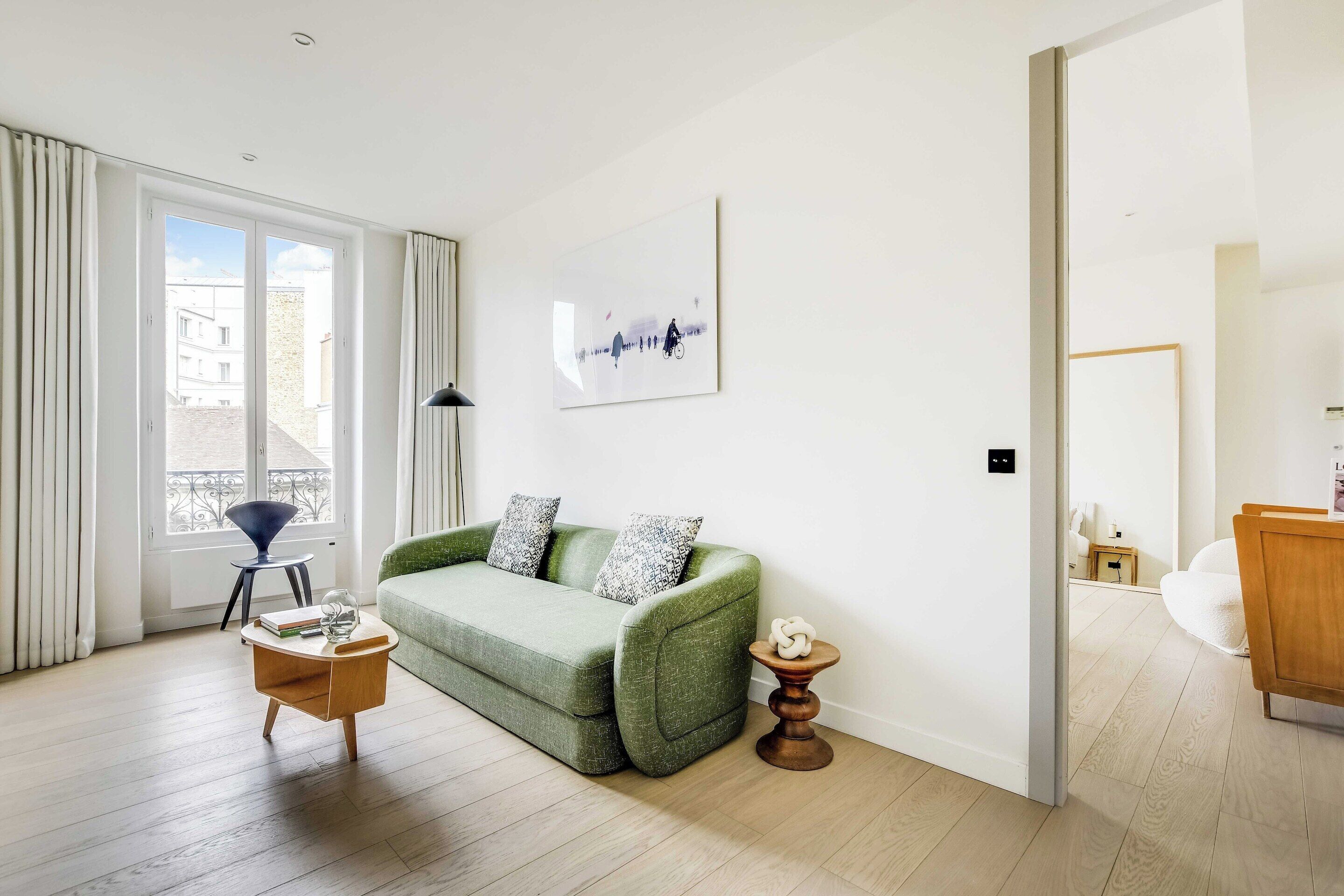 A modern living room with a green sofa, a coffee table, and a painting on the wall.