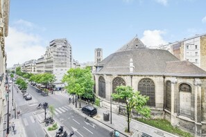 A street view with a building featuring arched windows and a tiled roof, surrounded by trees and other buildings. - Design Apartment 1br/4p - Le Marais (Paris)