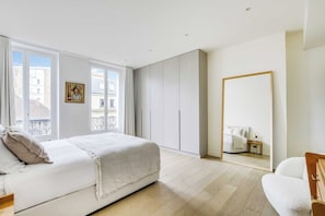 A bedroom with a bed, a wardrobe, a mirror, and a window. - Design Apartment 1br/4p - Le Marais (Paris)