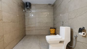 Une salle de bain équipée de toilettes, d’une douche et d’un porte-serviettes.