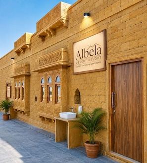 A desert resort with a signboard, a wooden door, and a sink area. - Albela Desert Resort  (Sam)