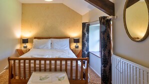 A bedroom with a wooden bed, bedside lamps, a nightstand, a mirror, and a window with curtains. - Spacious Devon Farmhouse (Exeter)