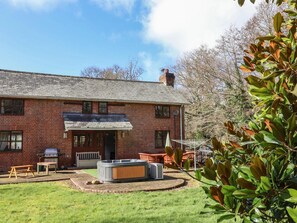 A brick house with a patio area, a hot tub, and a barbecue grill. - Spacious Devon Farmhouse (Exeter)
