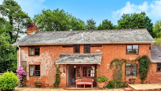 A brick house with a front porch, a bench, and a sign that reads 'Mill Cottage.' - Spacious Devon Farmhouse (Exeter)