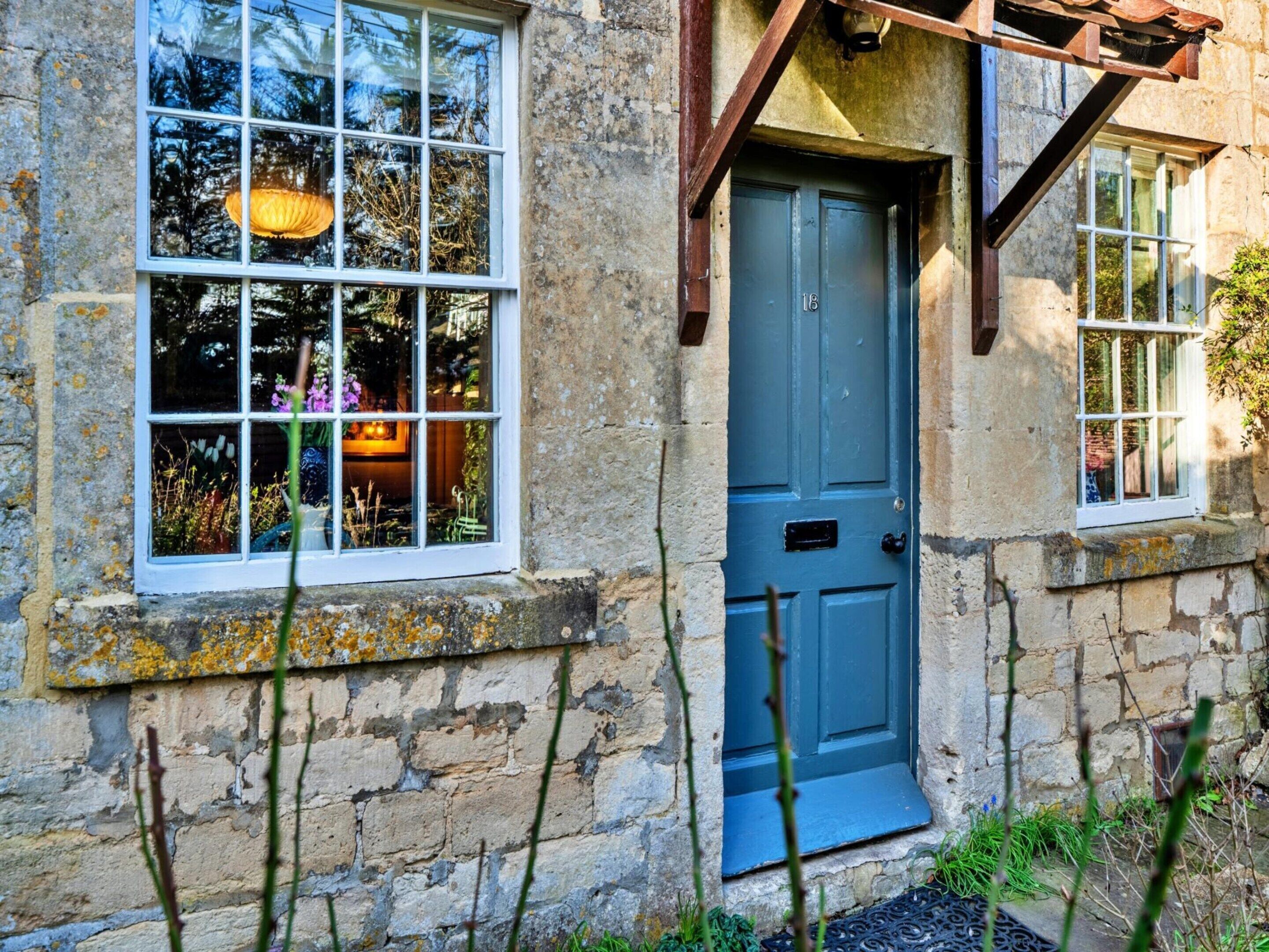 A stone building with a blue door, windows with white frames, and a small porch area.