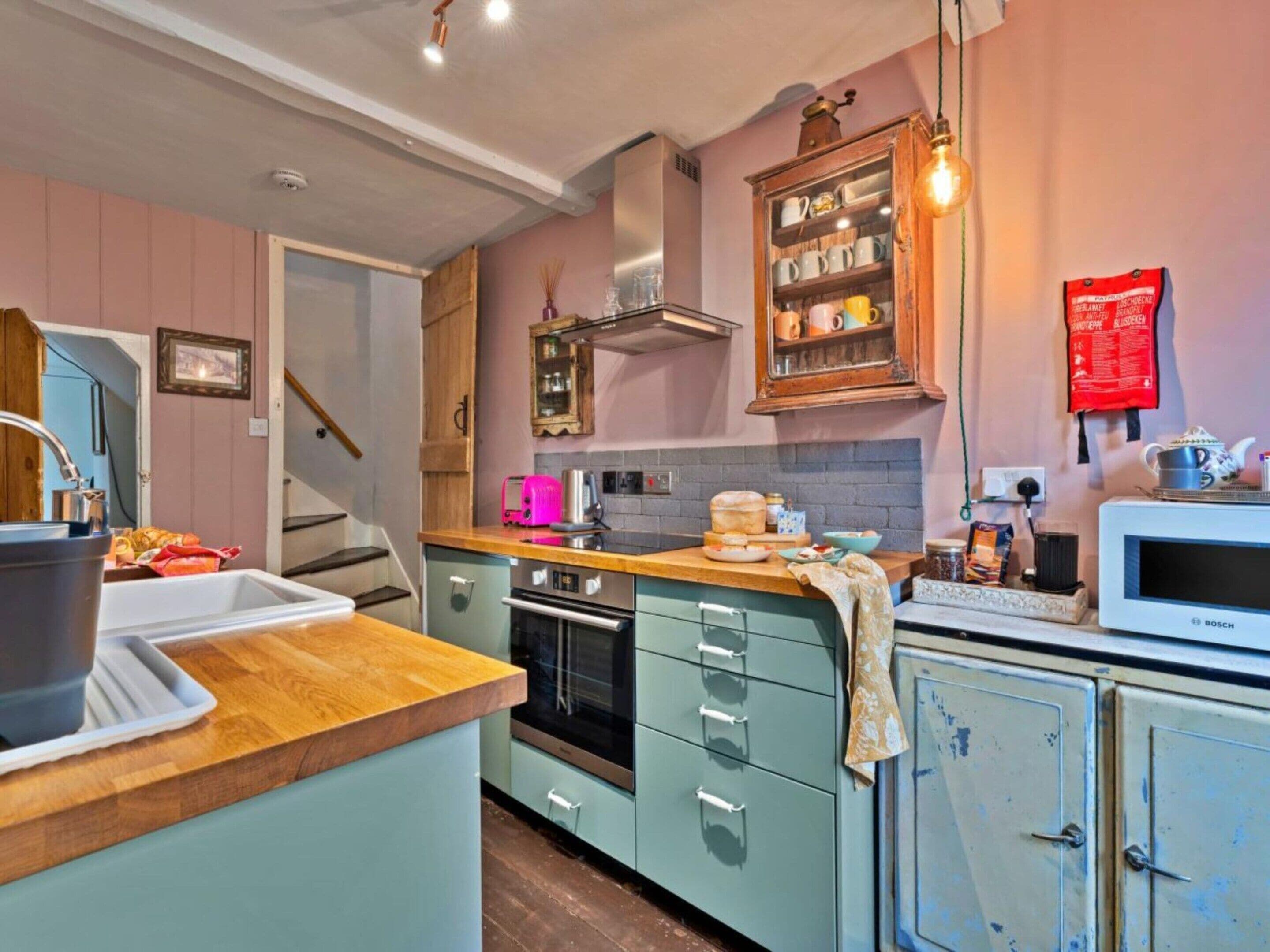 Une cuisine avec un plan de travail en bois, un évier, une cuisinière et des placards.