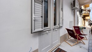 Un bâtiment à la façade blanche, une porte avec une poignée et une fenêtre avec des volets.