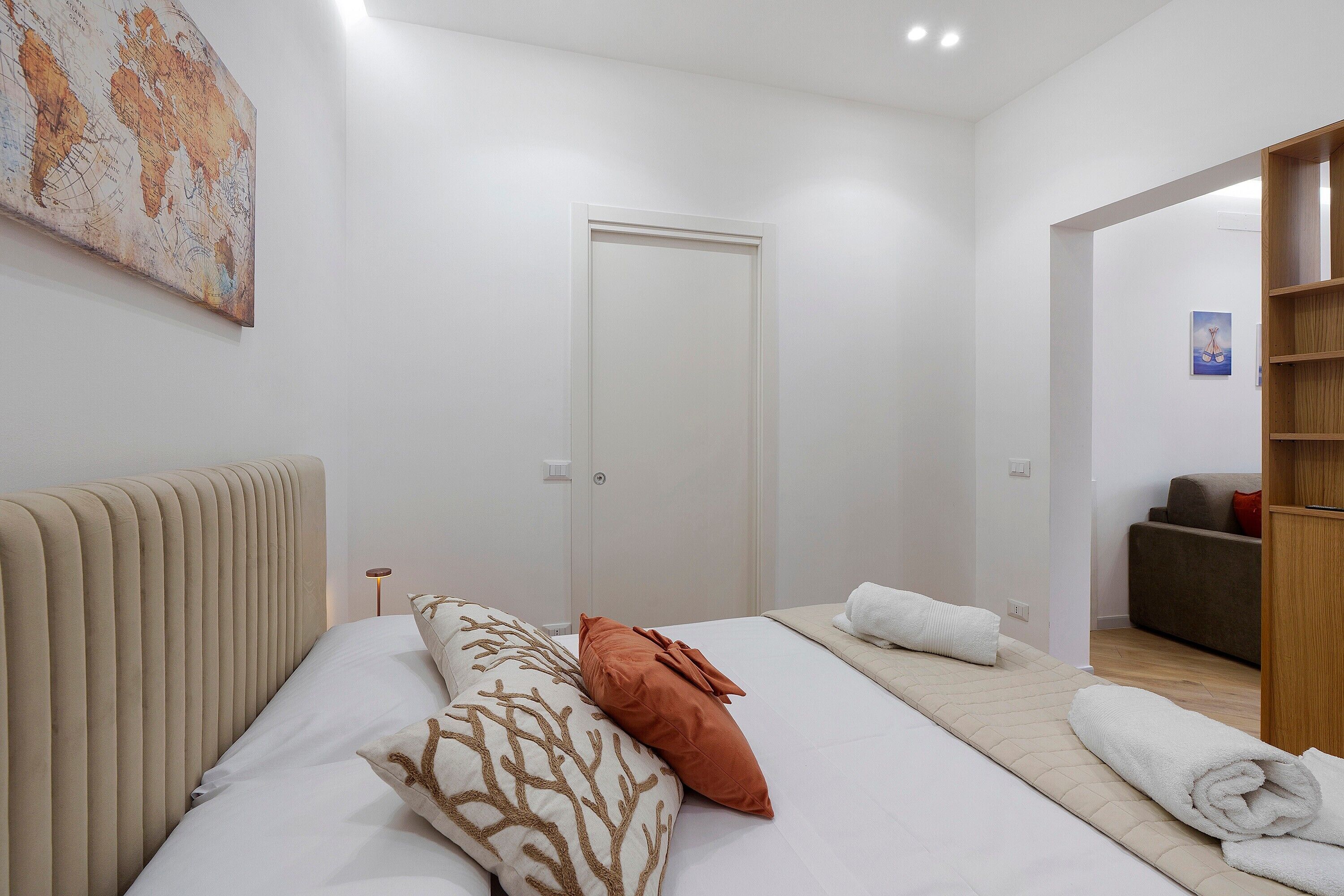 A hotel room with a bed, a bedside table, a lamp, a wardrobe, and a painting on the wall.