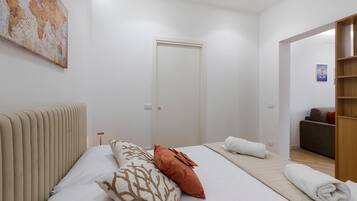 A hotel room with a bed, a bedside table, a lamp, a wardrobe, and a painting on the wall.