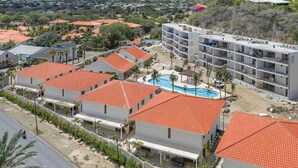 Ett semesterområde med flera byggnader, en swimmingpool och ett kuperat landskap i bakgrunden.
