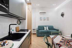 Un espace de vie compact comprenant un coin cuisine, un canapé et un coin repas.