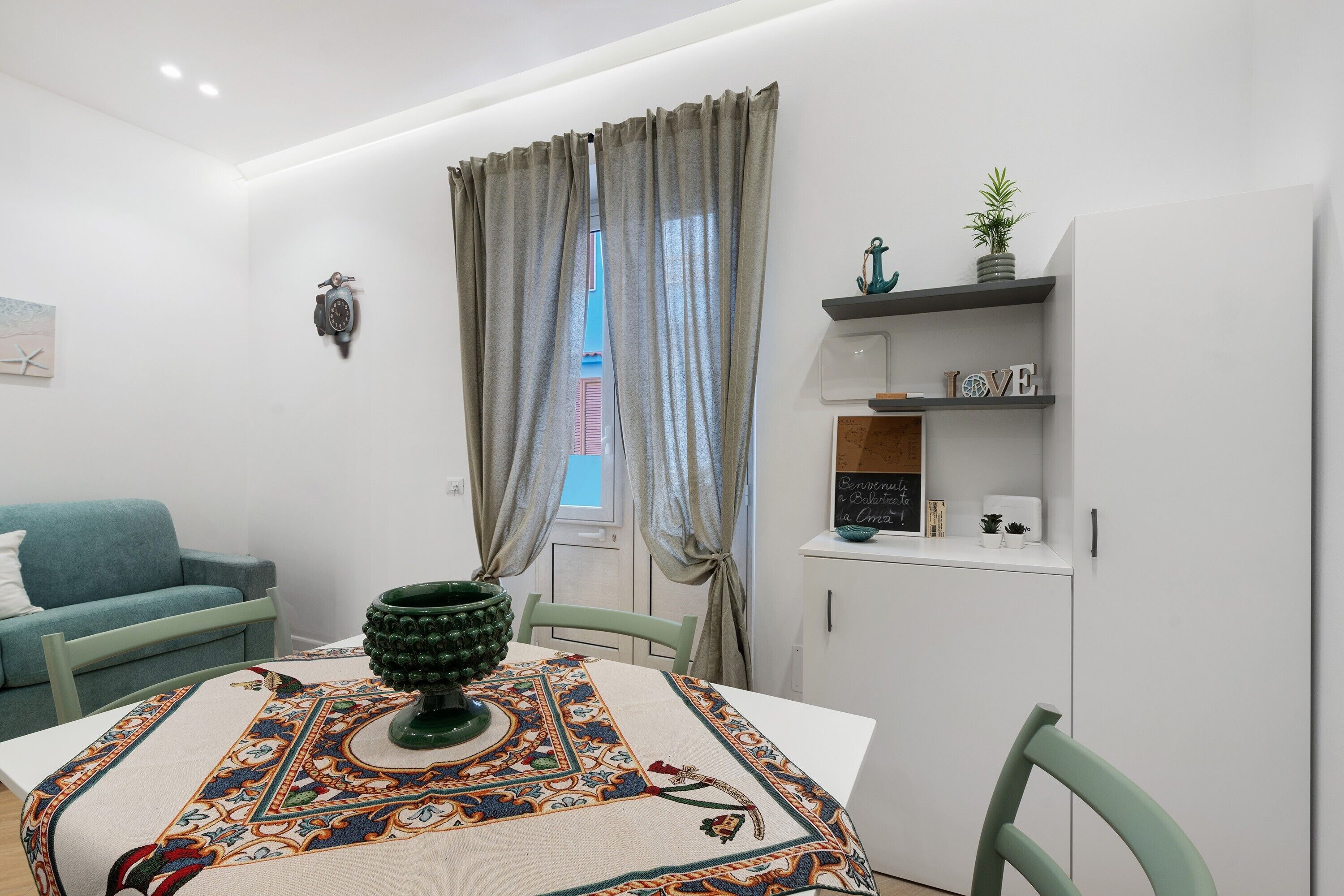 Un soggiorno moderno con un tavolo da pranzo, un divano e un mobile contenitore con oggetti decorativi.