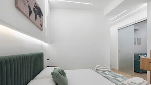 Ett modernt hotellrum med en snyggt bäddad säng, en grön sänggavel och en stor spegel.