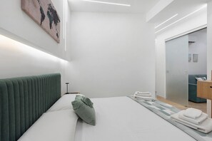 Ein modernes Hotelzimmer mit einem ordentlich bezogenen Bett, einem grünen Kopfteil und einem großen Spiegel.