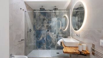 A modern bathroom with a glass-enclosed shower, a vanity with a wooden countertop, and a large mirror.