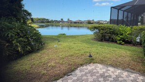 A landscaped area with a pond, grass, and a hexagonal paved walkway. - Minutes to the Sand! Pets! Charming 3-bedroom in beautiful Bradenton. (Bradenton)