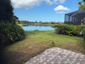 A landscaped area with a pond, grass, and a hexagonal paved walkway. - Minutes to the Sand! Pets! Charming 3-bedroom in beautiful Bradenton. (Bradenton)