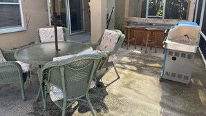 A patio with wicker furniture, a grill, and a covered area. - Minutes to the Sand! Pets! Charming 3-bedroom in beautiful Bradenton. (Bradenton)