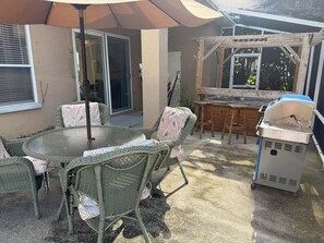 A patio with wicker furniture, a grill, and a covered area. - Minutes to the Sand! Pets! Charming 3-bedroom in beautiful Bradenton. (Bradenton)