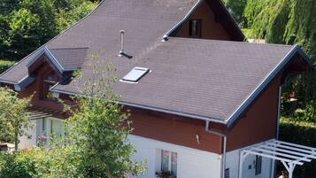 A two-story house with a sloped roof, a covered porch, and a car parked in the driveway.
