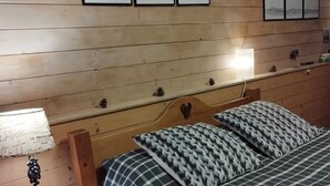 Una habitación con paneles de madera, una cama, una mesita de noche y obras de arte colgadas en la pared.