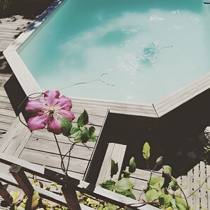 A swimming pool with a wooden deck and a pink flower. - Bed and Breakfast 'Chambre Paladru' with Mountain View, Shared Pool and Wi-Fi (Charancieu)