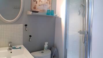 Een badkamer met douche, toilet, wastafel en een spiegel.