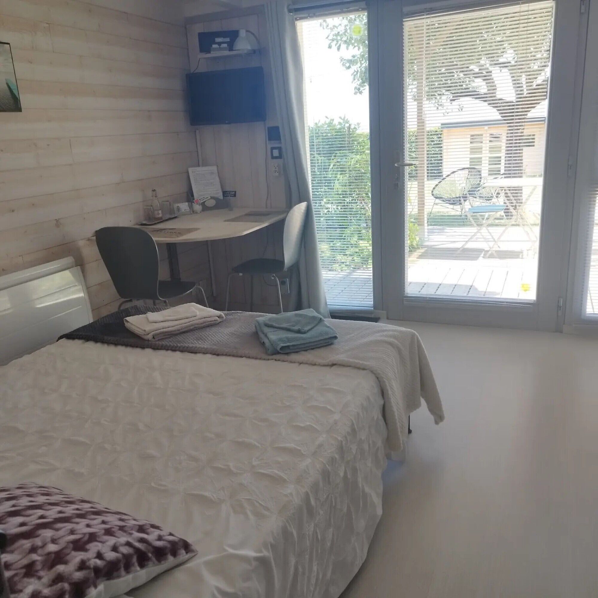 Ein Hotelzimmer mit einem Bett, einem Schreibtisch und Blick ins Freie.