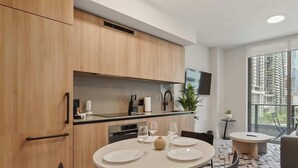 Eine moderne Küche mit Holzschränken, einem mit Tellern und Gläsern gedeckten Esstisch und einem großen Fenster mit Blick auf die Stadt.