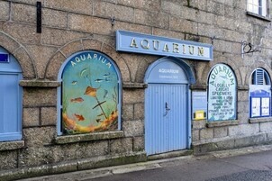 Un edificio con un letrero que dice 'AQUARIUM' y una puerta con cerradura.