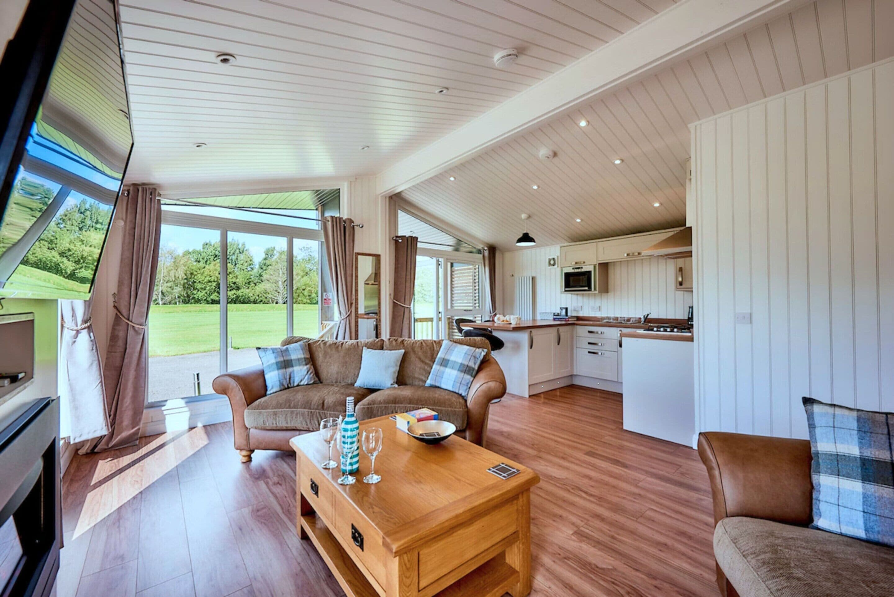 A spacious living area with a wooden coffee table, a sofa, and a kitchen in the background.