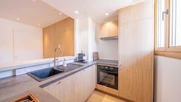 Una cocina moderna con armarios de madera, un lavamanos de acero inoxidable, horno empotrado y máquina de café.