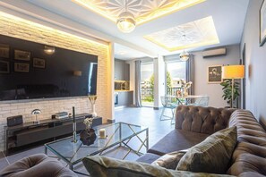Ein modernes Wohnzimmer mit Flachbildfernseher, Glastisch und Ledersofa.