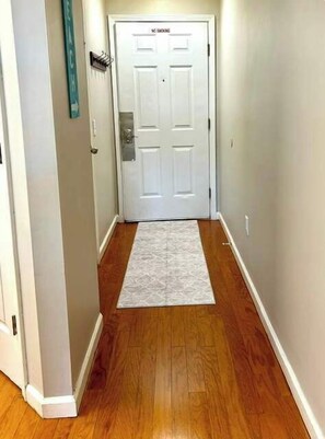 A hallway with a white door, a wooden floor, and a white rug. - Cozy Coastal Retreat With Scenic Waterway Views 16I (Myrtle Beach)