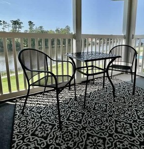 A balcony with a table and chairs, overlooking a body of water. - Cozy Coastal Retreat With Scenic Waterway Views 16I (Myrtle Beach)