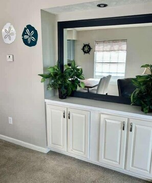 A room with a white cabinet, a mirror, and two potted plants. - Cozy Coastal Retreat With Scenic Waterway Views 16I (Myrtle Beach)