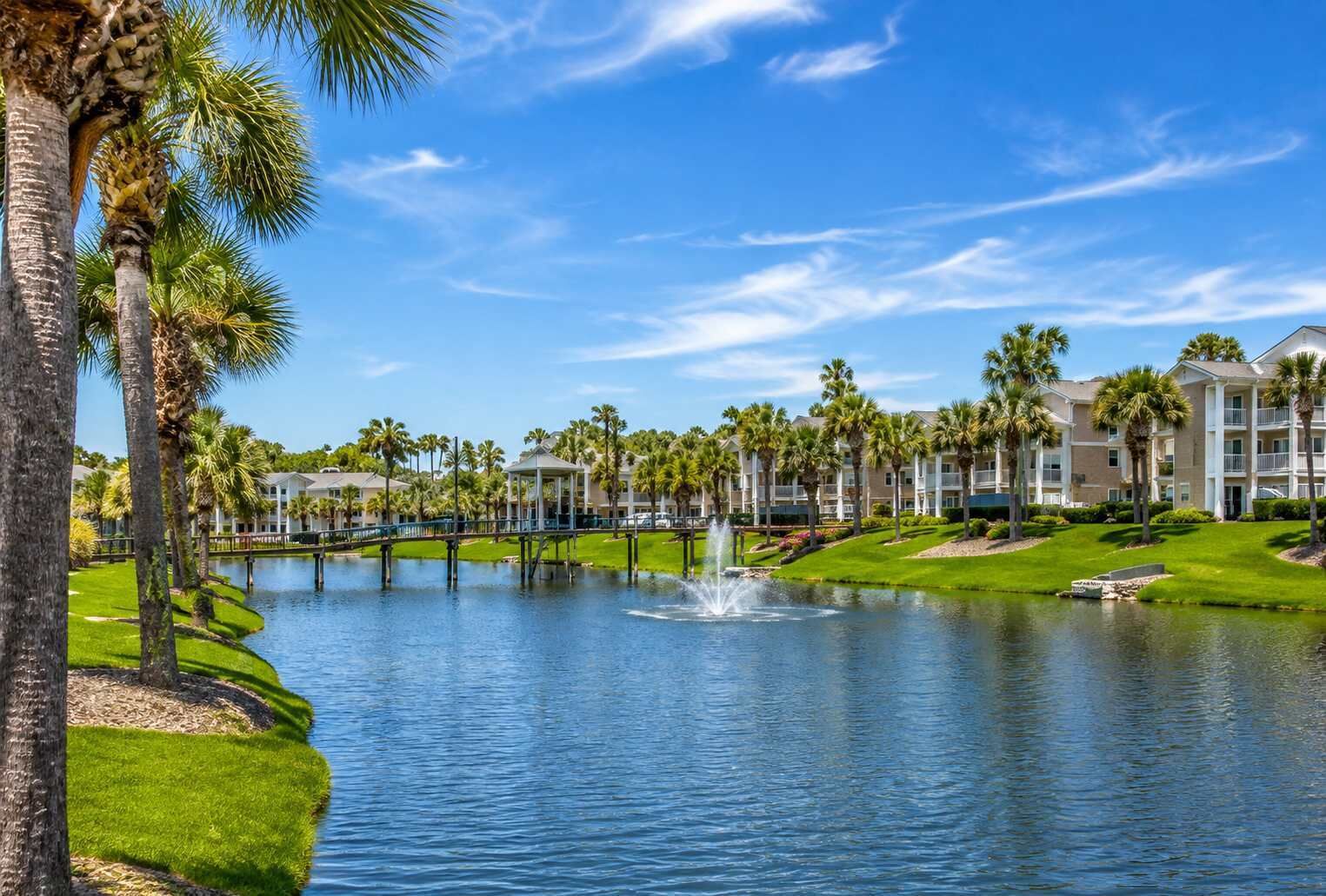 A waterfront hotel with a pool, palm trees, and a gazebo.
