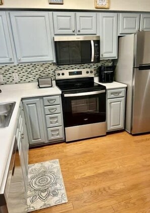 A kitchen with light gray cabinets, stainless steel appliances, and a patterned rug on the floor. - Cozy Coastal Retreat With Scenic Waterway Views 16I (Myrtle Beach)