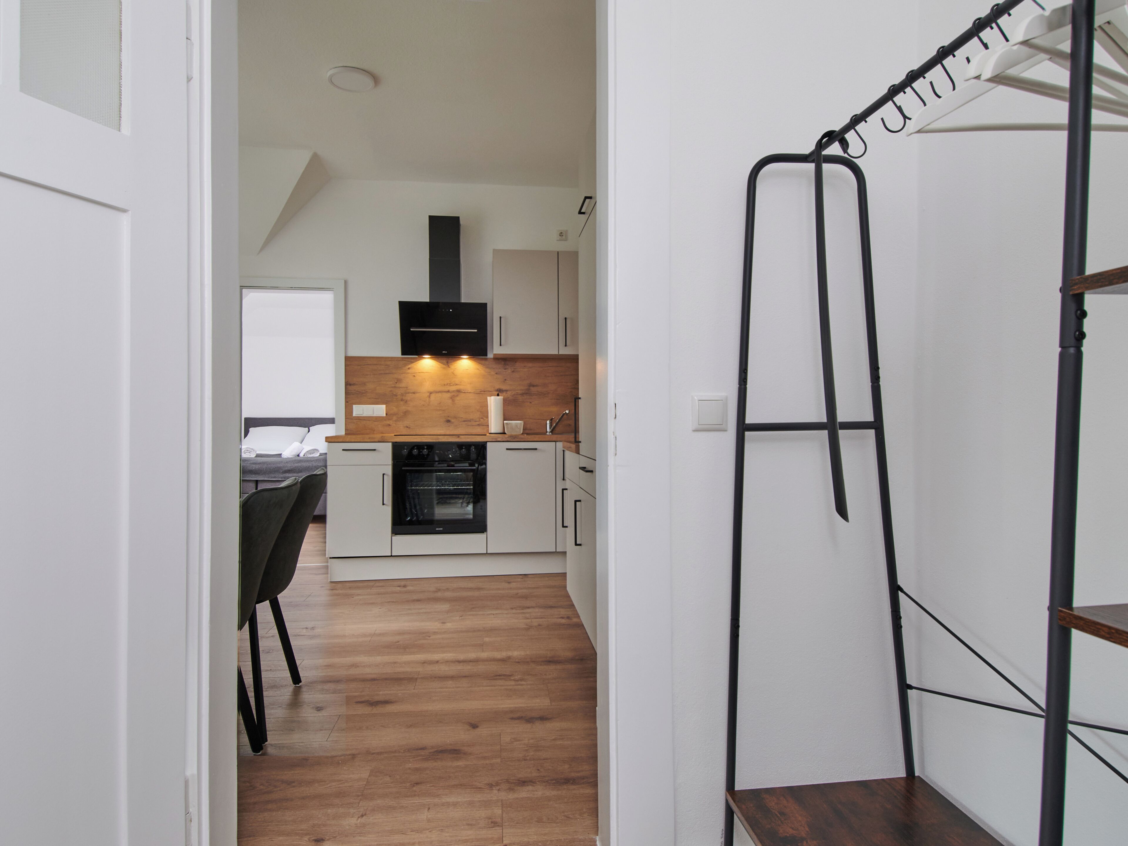 A modern kitchen with white cabinets, a wooden countertop, and a black range hood.