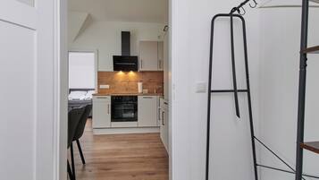 A modern kitchen with white cabinets, a wooden countertop, and a black range hood.