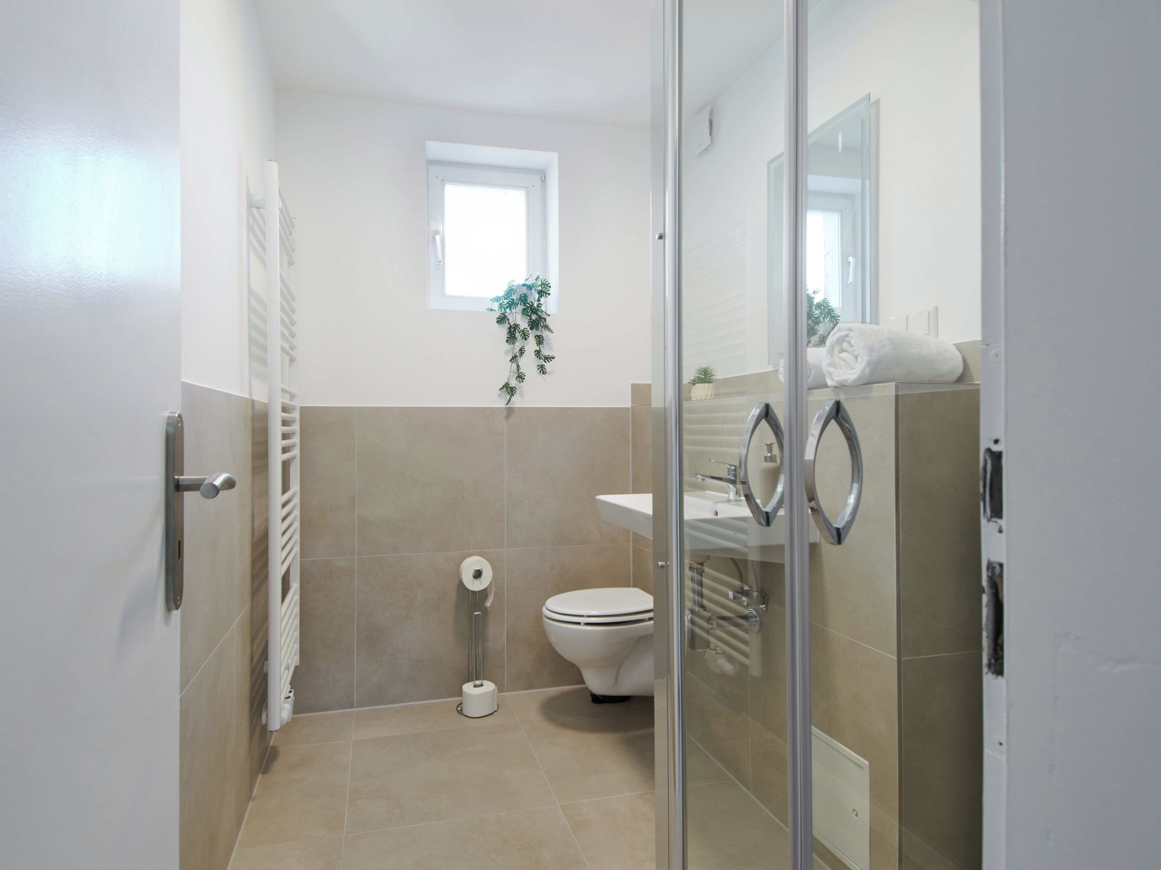 Et moderne badeværelse med en glasbrusekabine, toilet og håndvask.