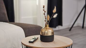 A round table with a remote control and a vase with dried plants.