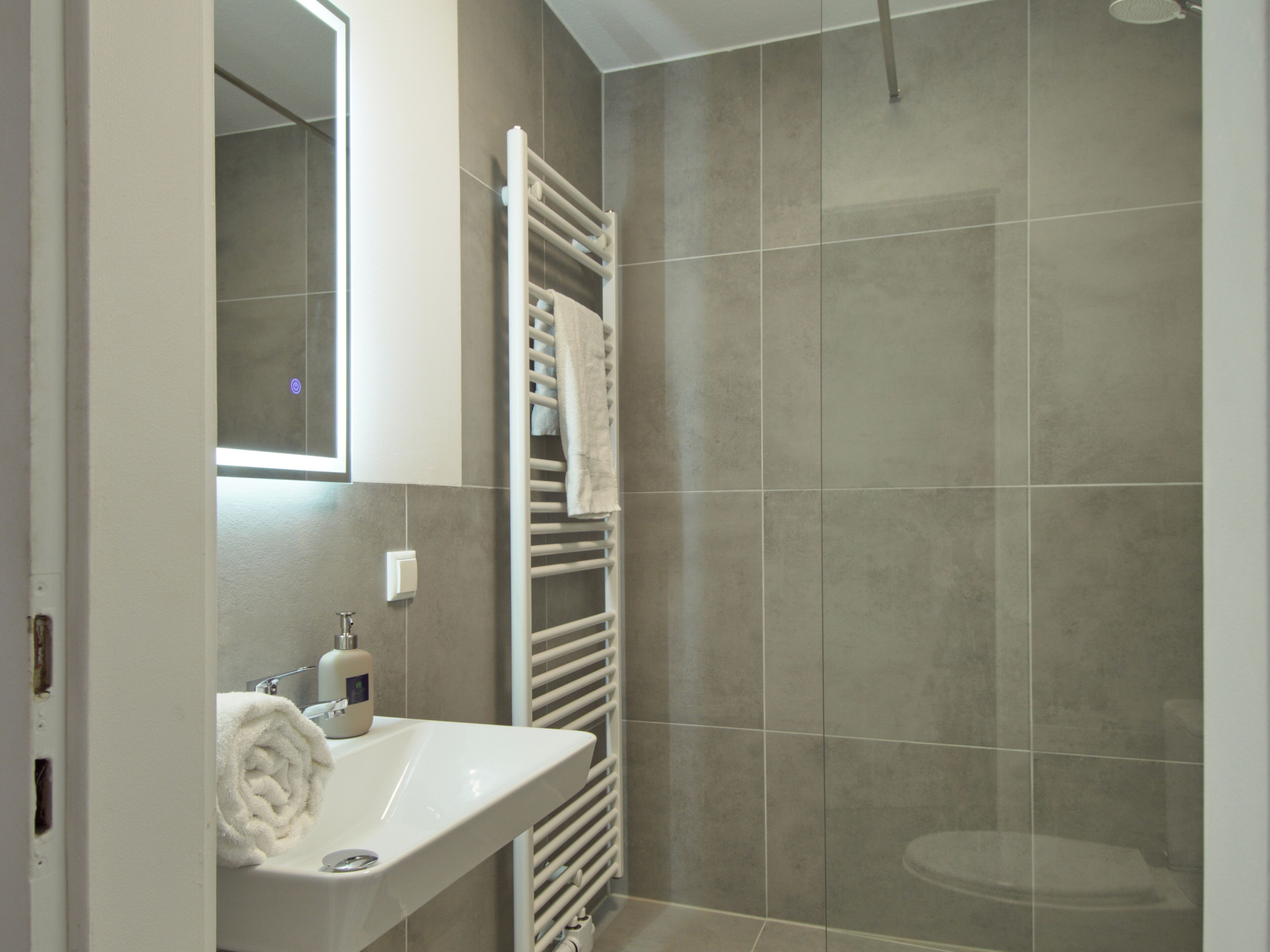 A bathroom with a white sink, a towel rack, and a shower area.