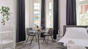 Ein Hotelzimmer mit einem Bett, einem runden Tisch mit Stühlen, einem kleinen Beistelltisch und einer Pflanze.