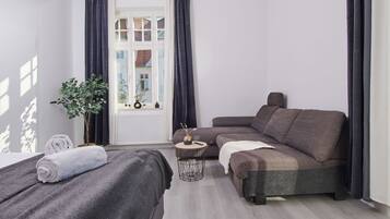 A modern bedroom with a sofa bed, a small round table, and a potted plant.