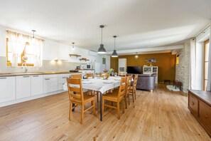 Una cocina moderna con armarios blancos, una mesa de comedor lista para seis personas y una pared decorativa de piedra.