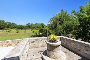 A stone structure with a potted plant on top, surrounded by a stone wall and a grassy field. - Villa Lanca by Villa Plus (Heraki)