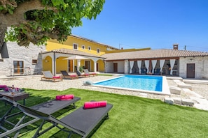 A poolside area with lounge chairs, a small pool, and a stone building with a tiled roof. - Villa Lanca by Villa Plus (Heraki)