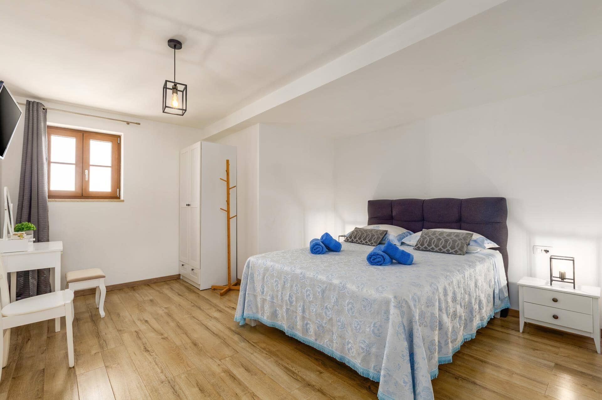 A bedroom with a bed, bedside table, and a wardrobe.